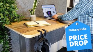 A person working at a Vari standing desk with a "price drop" badge