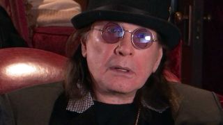 Ozzy Osbourne on a sofa wearing a bowler hat