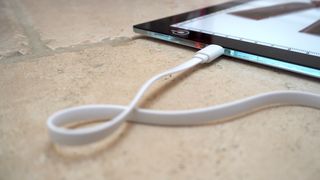 Close up of the USB cable connection to a Huion L4S light pad on a beige stone slab surface