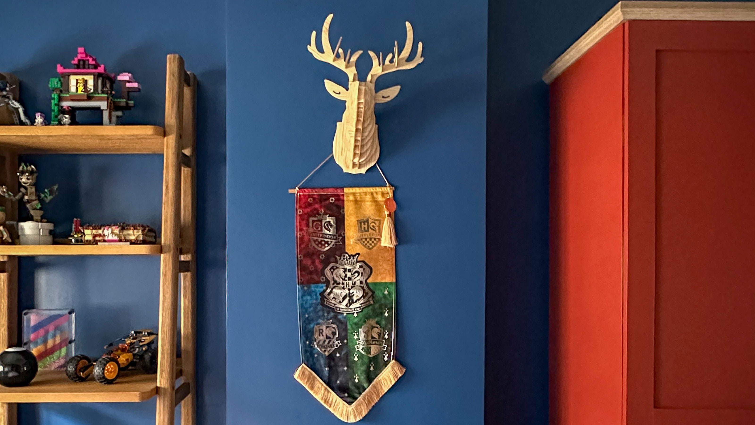 Blue boys room with wooden furniture, red wardrobe, deer head style wall decoration and Harry Potter wall hanging