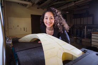 Graduate student Karly Bast sitting next to the model of da Vinci's bridge her and her team built .