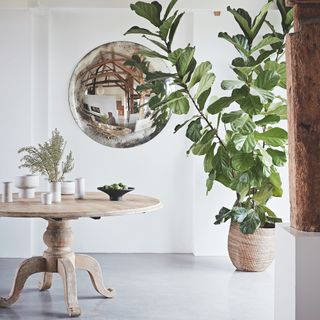 room with white wall and round mirror and pots and round table