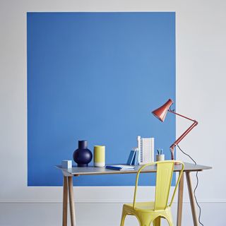 square blue paint wall with lamp on desk and chair