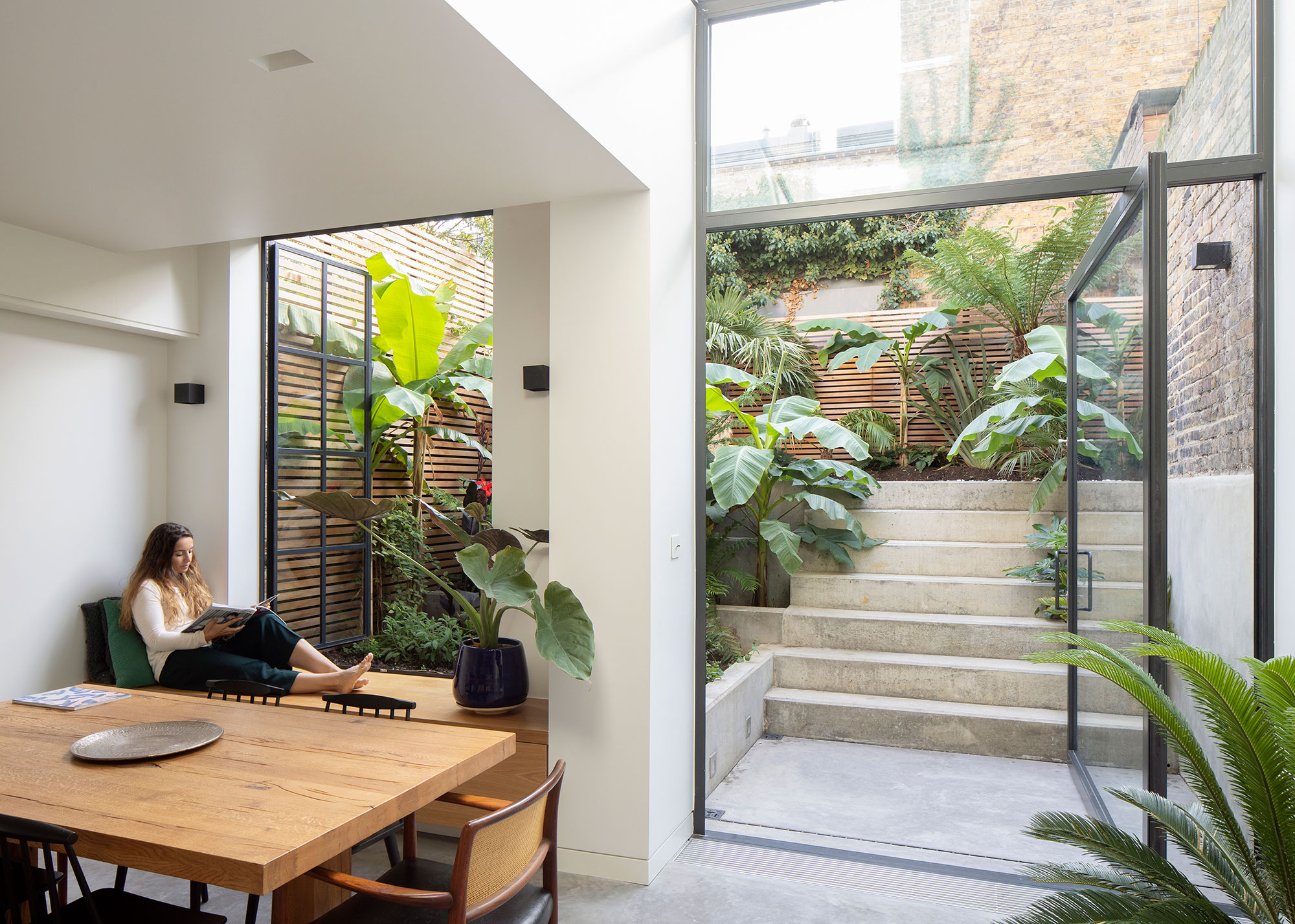 open plan dining space with oversized pivot door leading to sunken garden