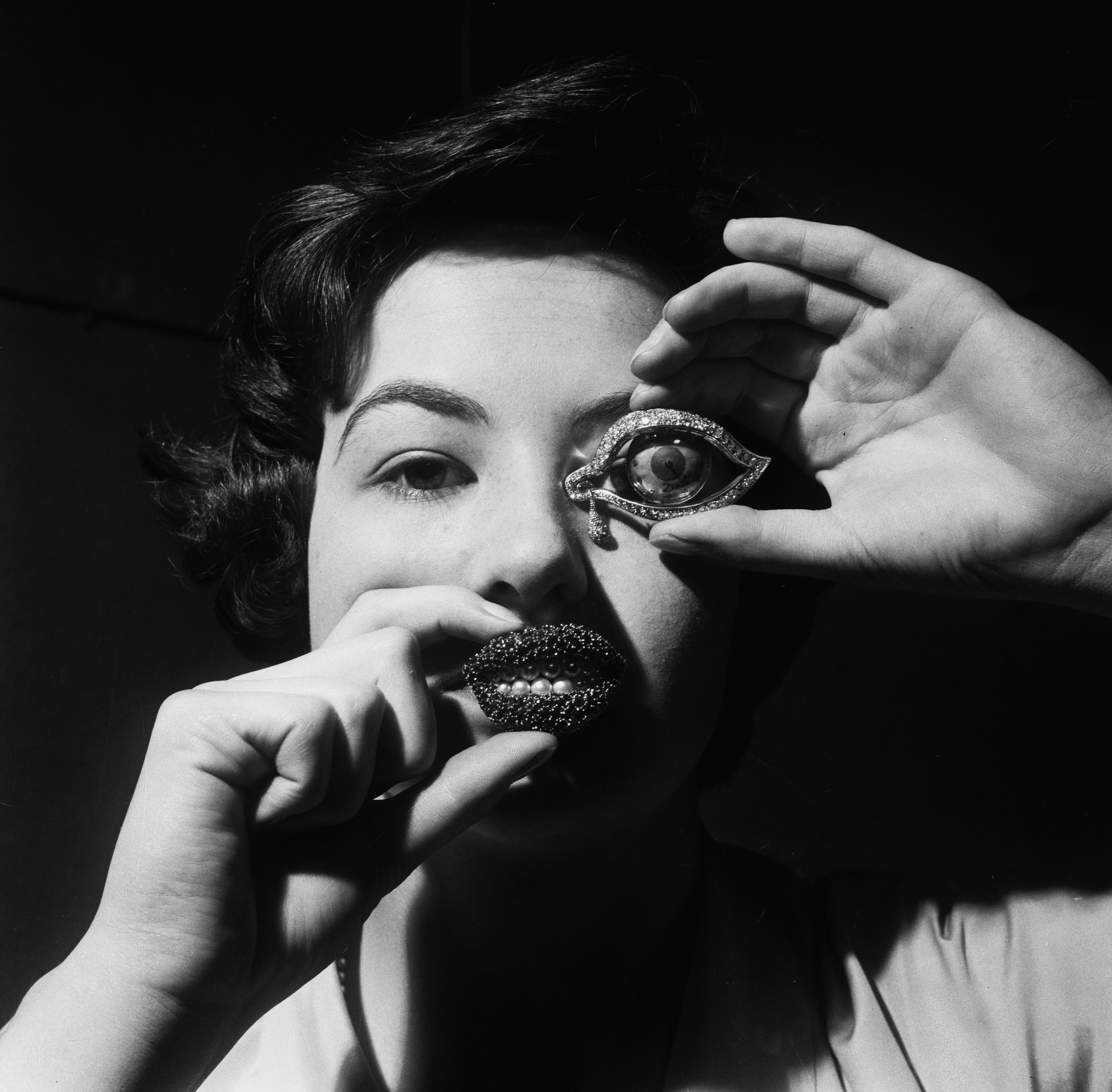 A woman holding up two brooches from a jewellery collection designed by Spanish artist Salvador Dali