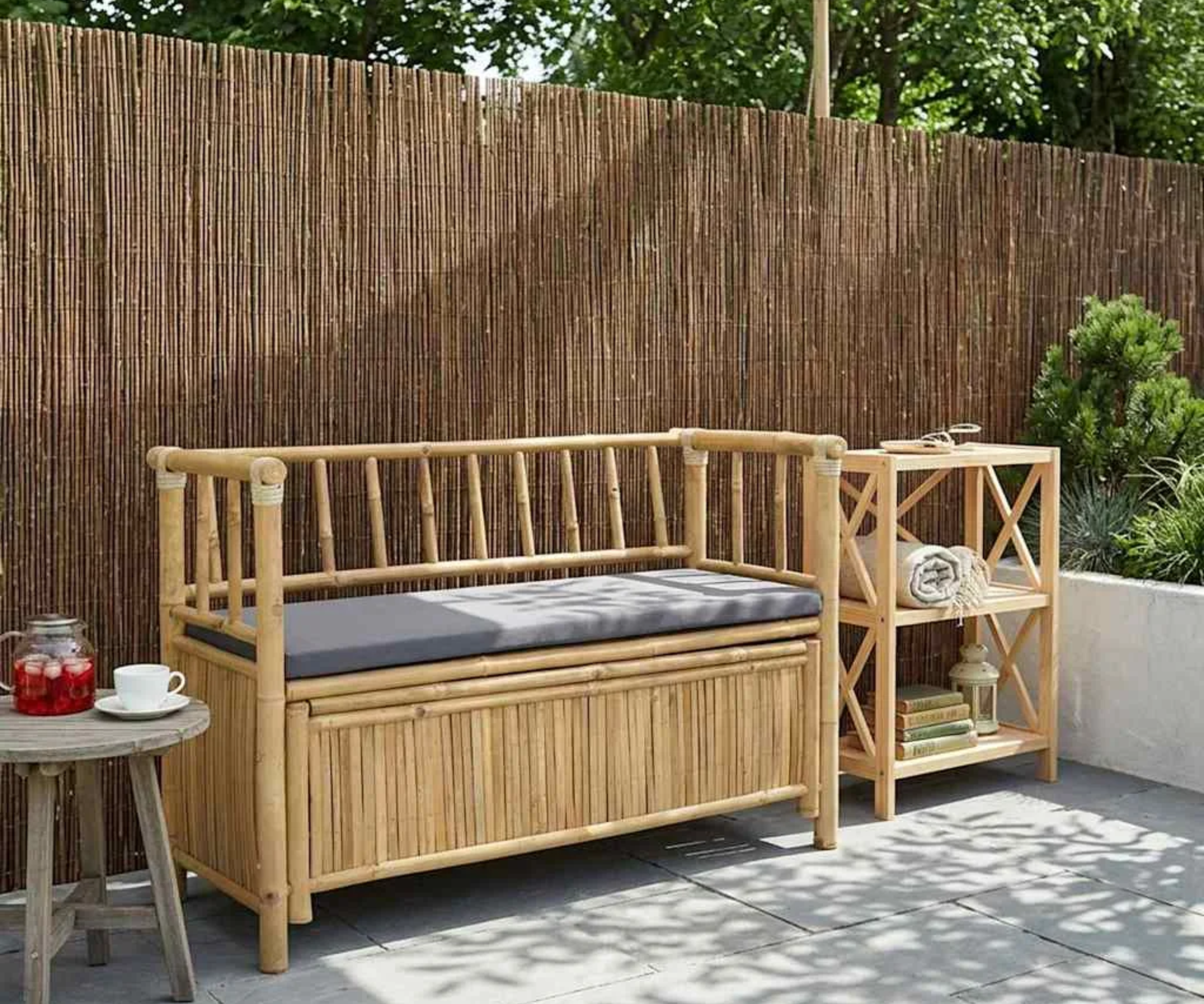 Bamboo storage bench with grey cushion in a garden on a patio