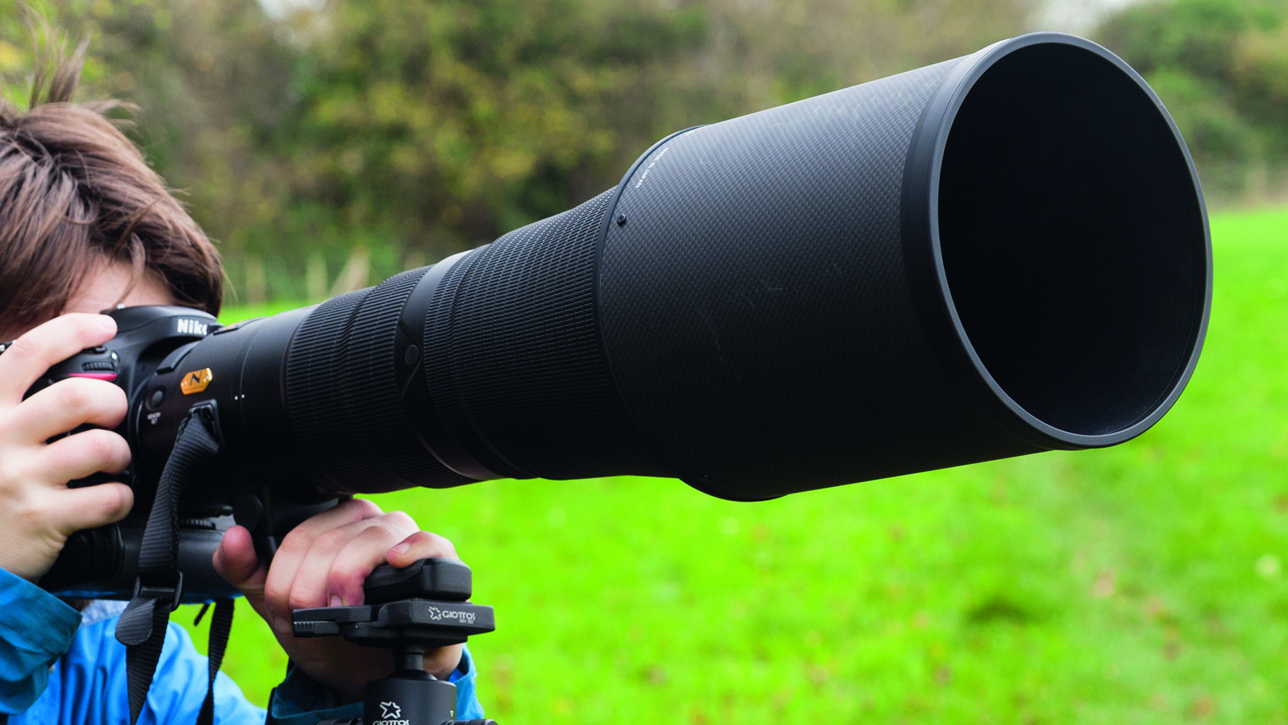 A person looking through an ultra zoom lens, which is mounted on a tripod