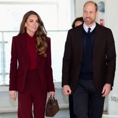 Princess kate wearing a maroon suit walking next to Prince William