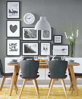 A grey dining space with a wooden table, grey chairs and a picture gallery hanging on the wall