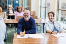 A mixed age group laughs as the teacher uses humor to introduce the resume writing class.