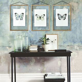 textured wall with butterfly prints and black table with glass jar