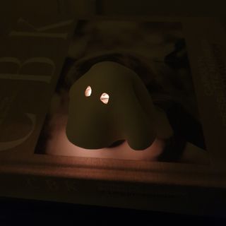 A ghost-shaped tea light cover made from air dry clay glowing in the dark