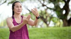 Woman wearing activewear and watch doing Tai Chi for sleep in park