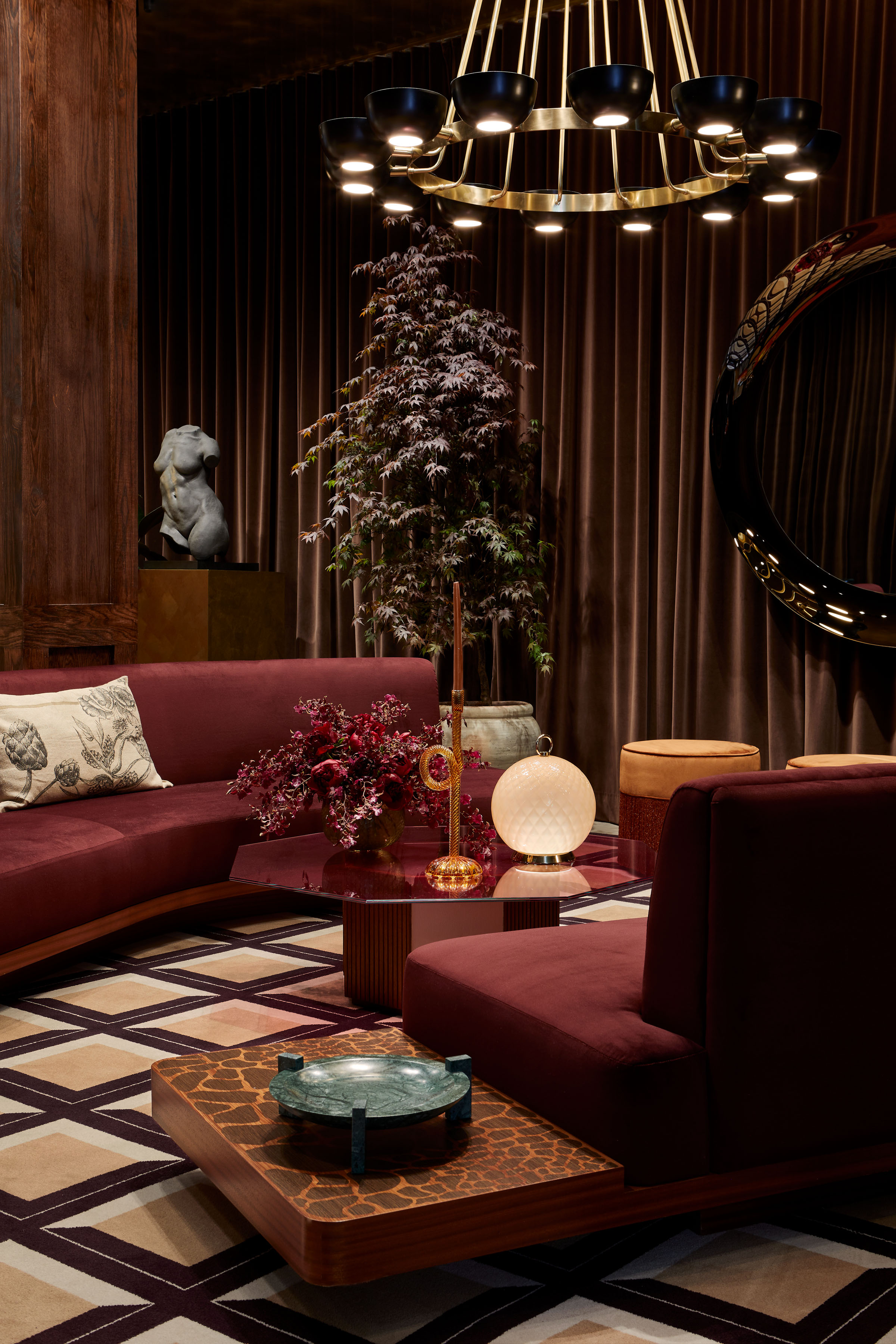A plushly decorated design showroom features velvety cherry tones, chequered carpeted floors in cream and black, and Art Deco accessories bringing the space to life.