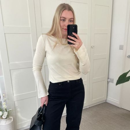 Woman wears yellow top, black jeans, carries black bag