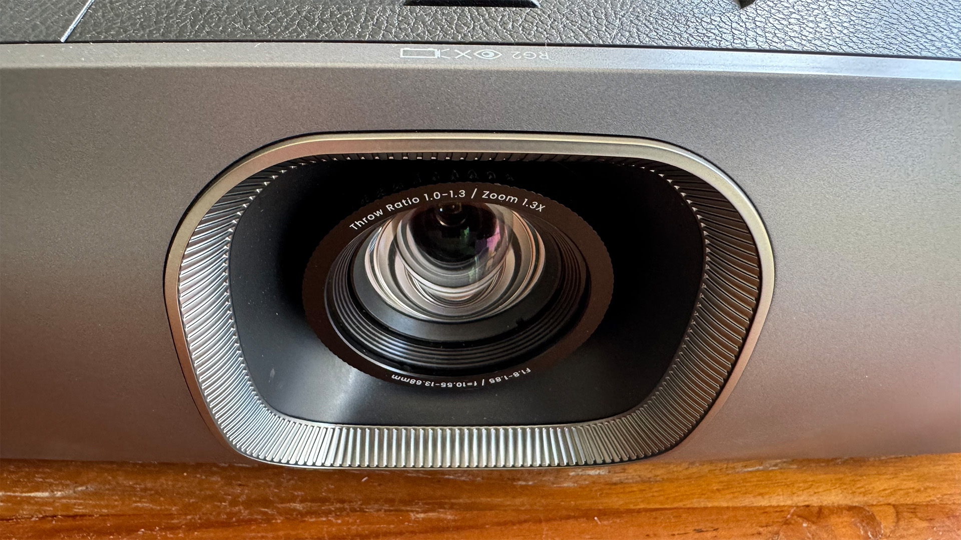 The BenQ W2720i projector, pictured on a wooden table in a living room