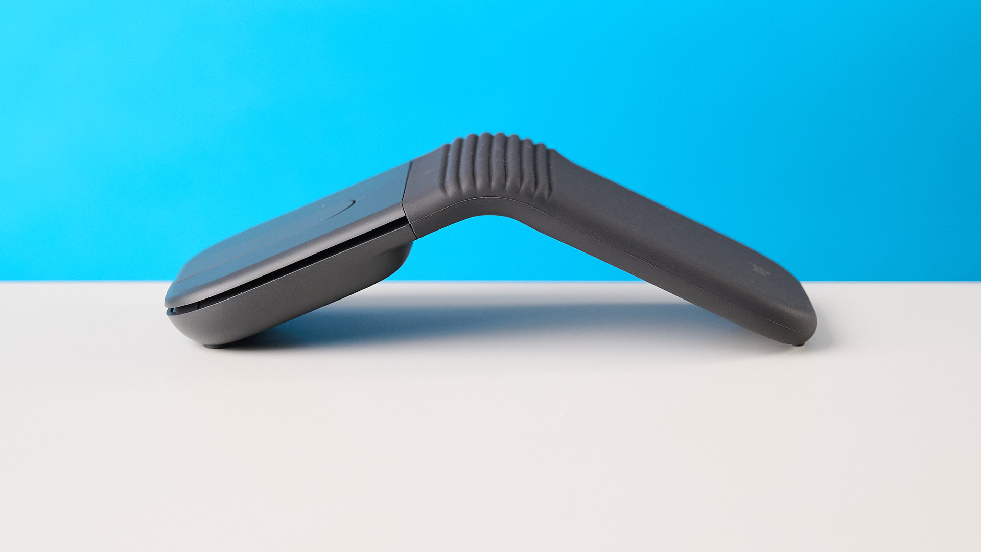 Logitech Mobi Fold mouse in graphite photographed in front of a blue background
