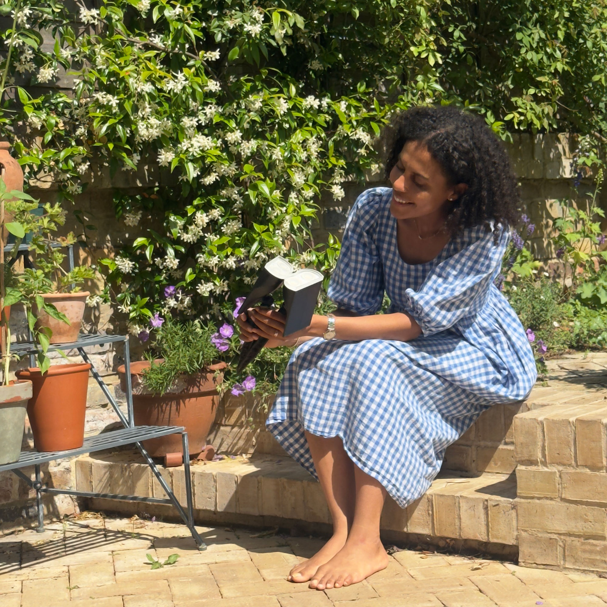 Woman in blue dress sitting on step in garden holding wireless lights