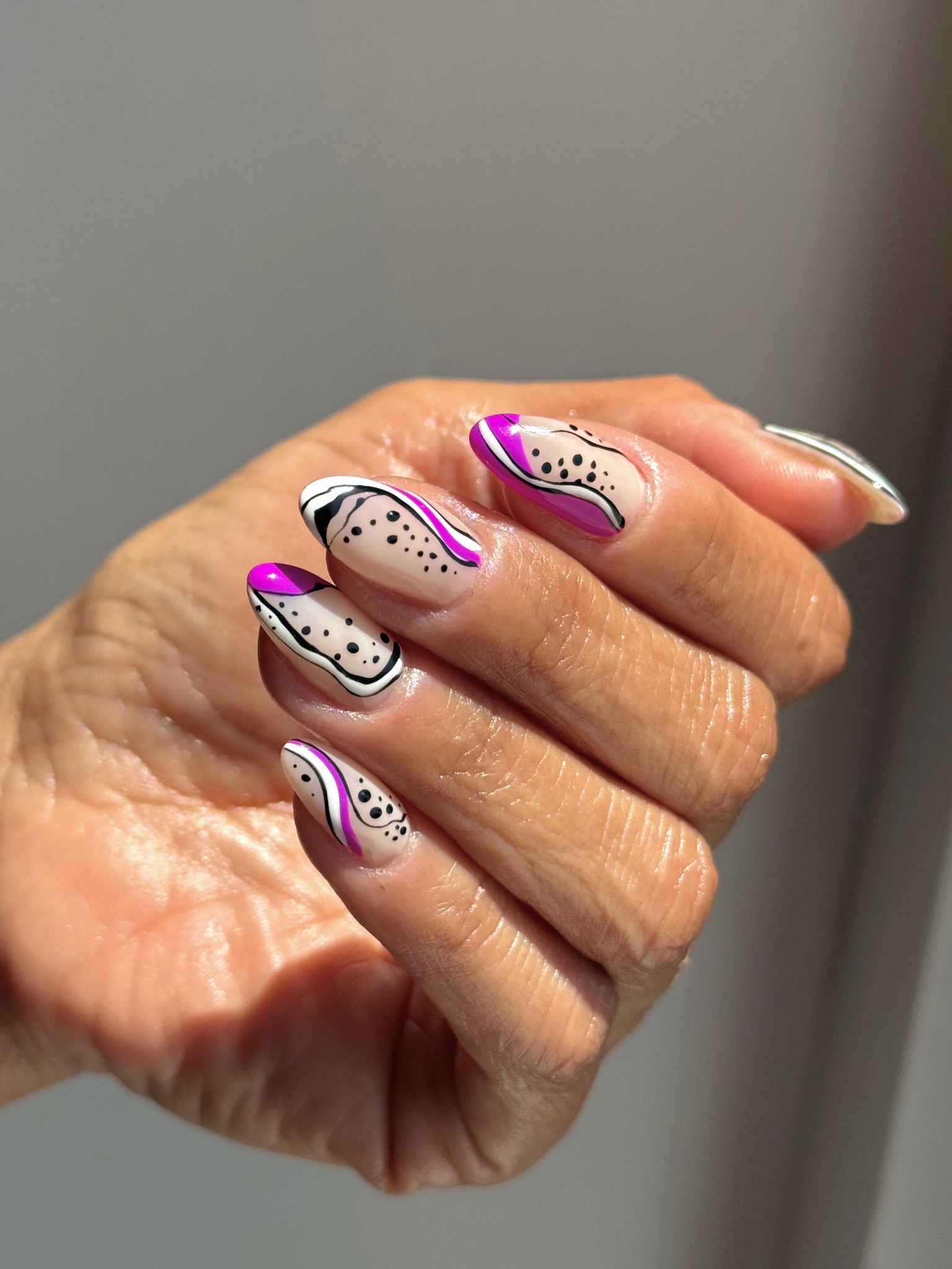 A close-up picture of a purple, black and white swirl nail design