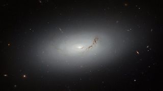a glowing with galaxy hangs center amongst small, distant dots, which are also galaxies.