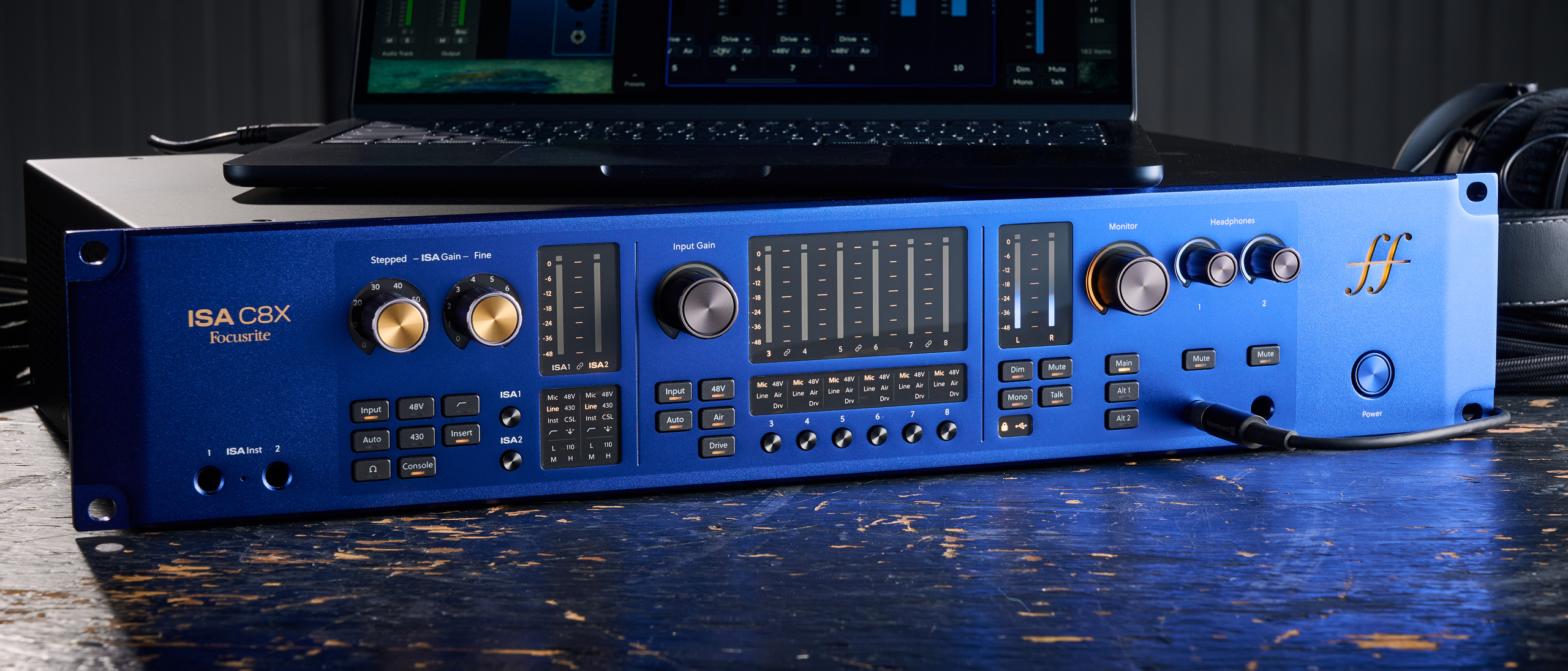 A Focusrite ISA C8X audio interface on a worn wooden desk with a laptop on top of it