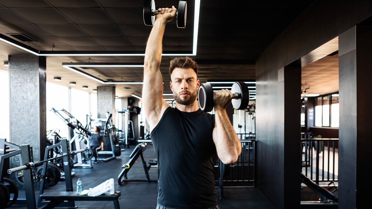 A man performing an Arnold press in the gym as part of his full-body workout