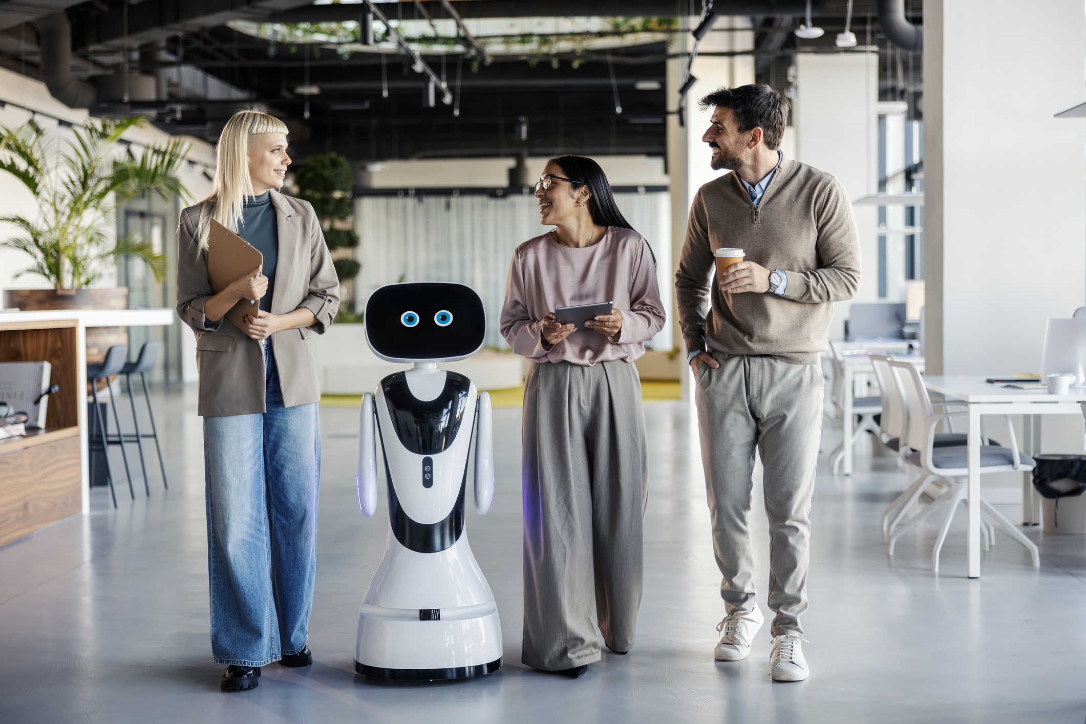 business people and a service robot walking together through a contemporary open-plan office, discussing work and technology