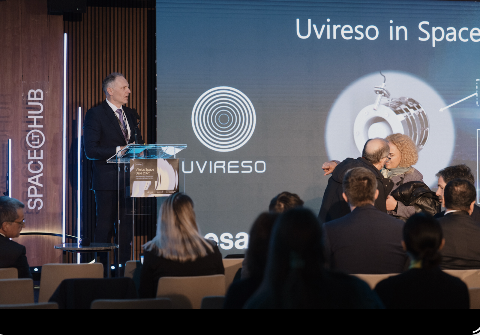 A person standing at a podium. in the background, it says "uvireso in space."
