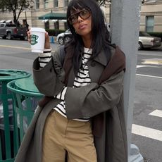 Woman in trench coat, striped tee, and khaki pants