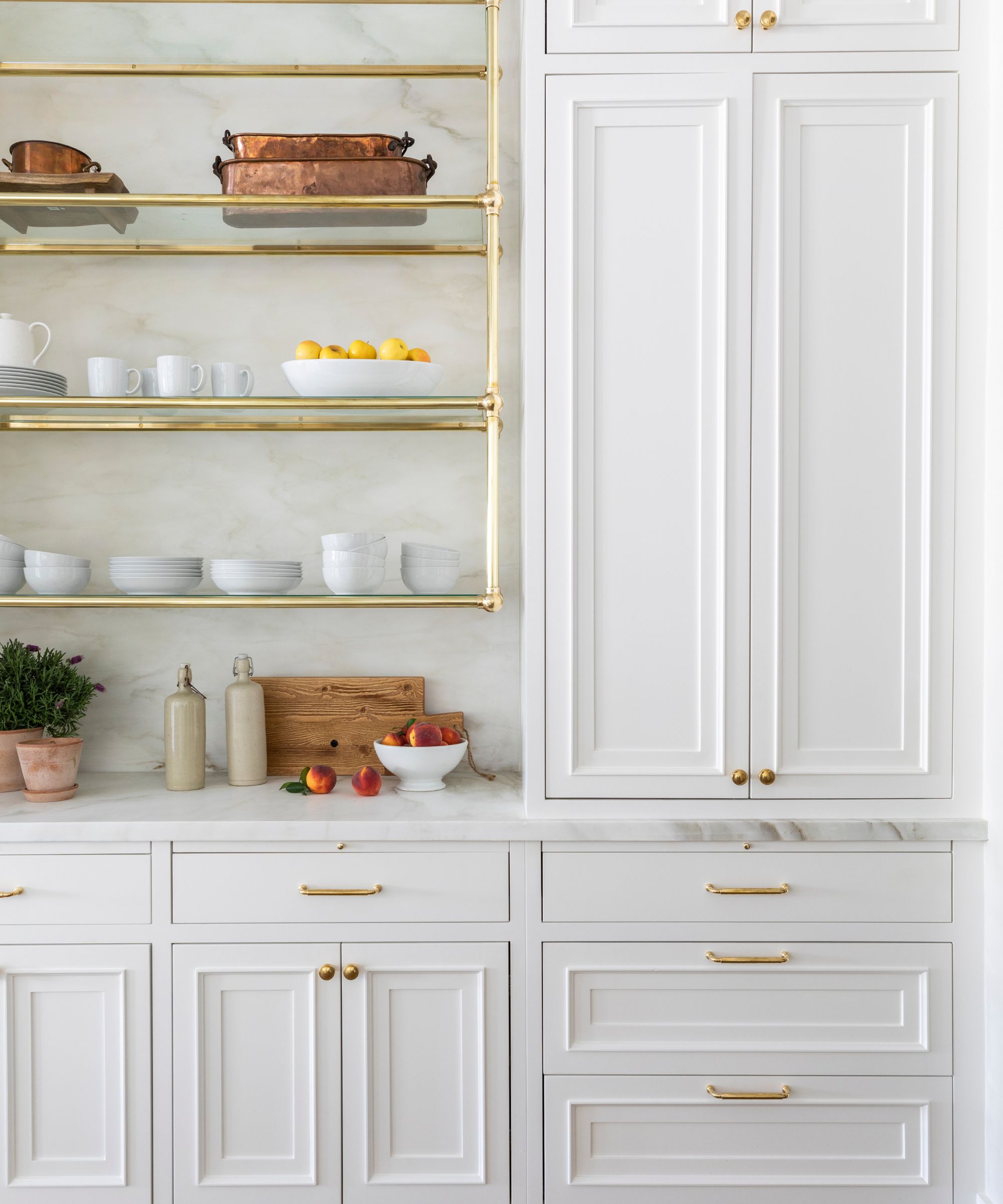 white kitchen cabinetry with gold hardware and marble countertops, gold upper shelving unit