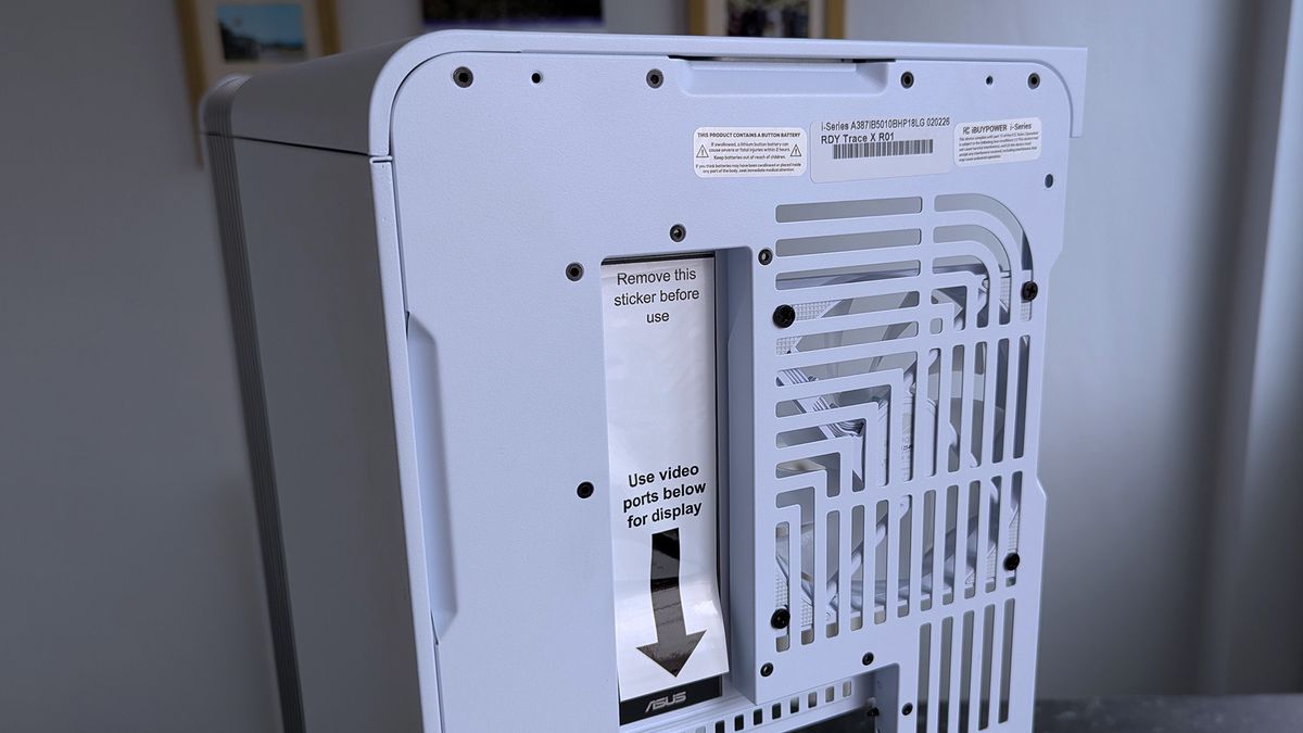 The back of a white iBUYPOWER RDY Trace X R01 computer with vented slots and a shiny sticker that reads, "Remove this sticker before use."