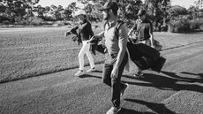 Golfers walk in black and white