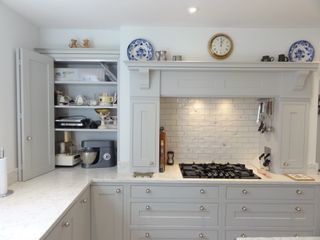 White bifold kitchen cabinet doors in white space with marble countertops and tiled splashback