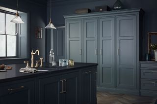 dark blue kitchen with kitchen island, cabinetry, herringbone floor, glass ceiling lights