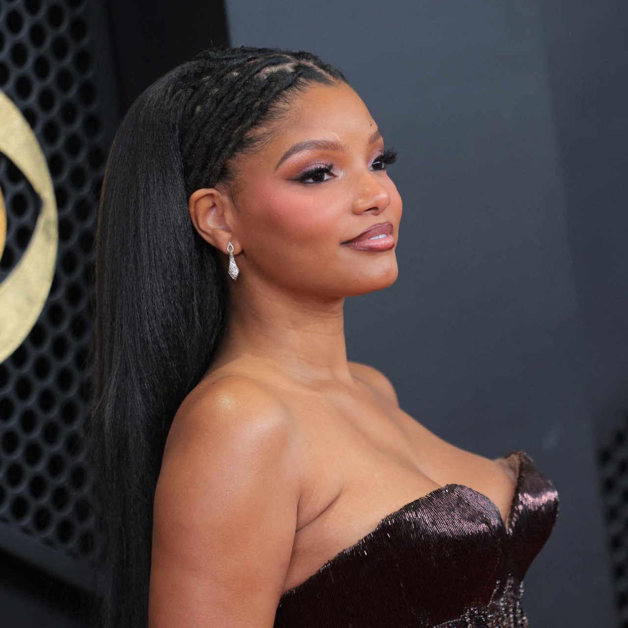 a young black woman with long, black hair poses on the red carpet at the grammy awards