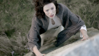 claire touching a standing stone to time travel in outlander's pilot