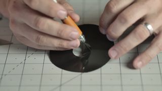 A homemade floppy disk under construction, with a scalpel being used to remove the center