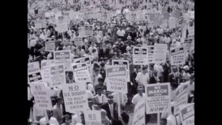 A black and white photo of a crowd of people protesting.
