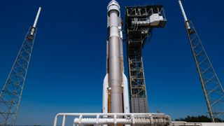 photo looking up at a brown and white rocket, with blue sky in the background