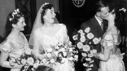 Groom kissing 1 bride while other brides look on