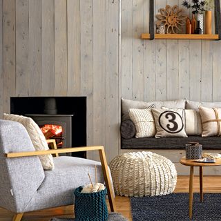 Living room with wooden wall panelling, built in bench and wood burning stove