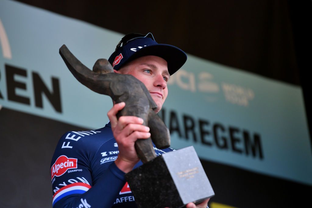 WAREGEM BELGIUM MARCH 30 Mathieu Van Der Poel of Netherlands and Team AlpecinFenix celebrates with a trophy at podium as race winner during the 76th Dwars Door Vlaanderen 2022 Mens Elite a 1837km one day race from Roeselare to Waregem DDV22 DDVmen WorldTour on March 30 2022 in Waregem Belgium Photo by Luc ClaessenGetty Images