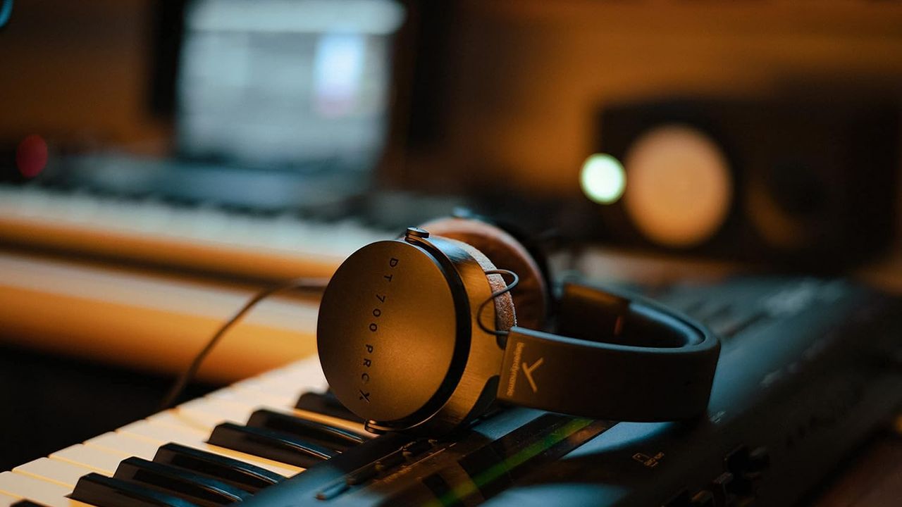 The Beyerdynamic DT 700 Pro X over-ear headphones lying on a keyboard in a music studio.