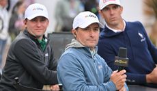 Kevin Kisner watches a golf shot with a CNBC hat on