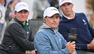 Kevin Kisner watches a golf shot with a CNBC hat on