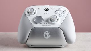 GameSir G7 Pro in charging dock, on a white desk with pink wall in background