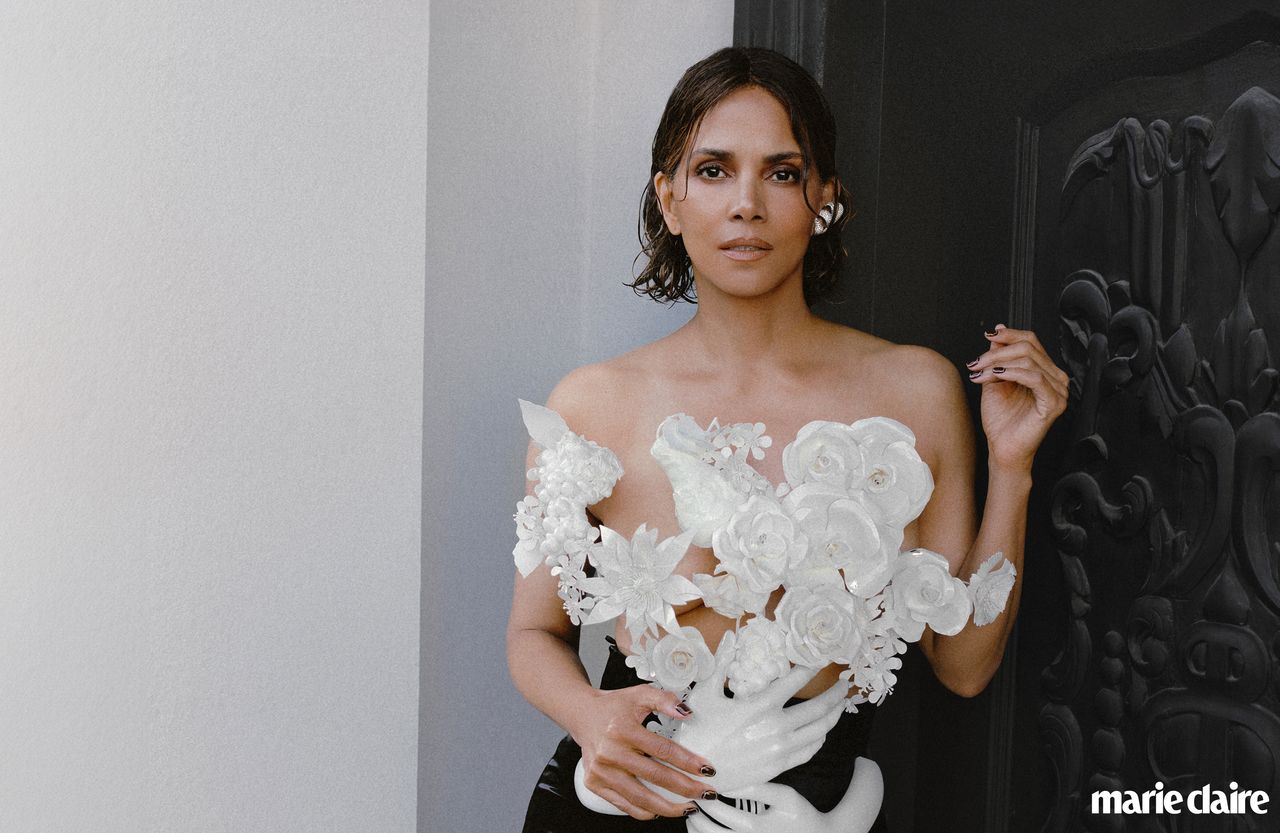 Halle Berry leans against an ornate black door wearing a floral die-cut top by Balmain