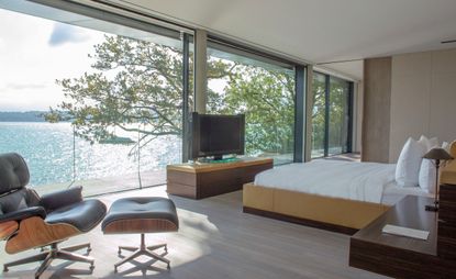 A bedroom with large windows and view of water