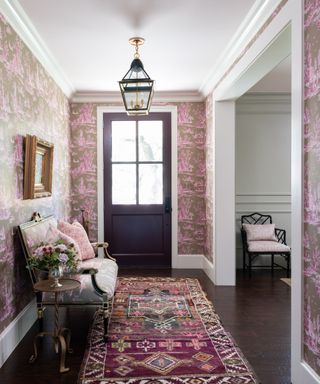 entryway with pink patterned wallpaper, pink rug, purple front door