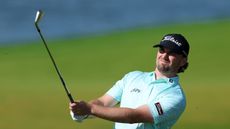 Cameron Adam hits an iron shot and watches it